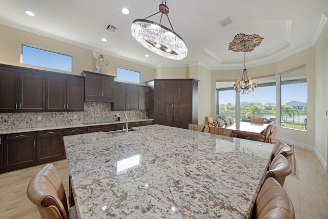 4673 Estates Cir, Westlake, FL 33470 - kitchen with a chandelier, a kitchen bar, crown molding, dark brown cabinetry, and decorative backsplash