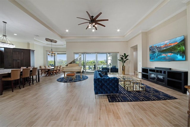 4673 Estates Cir, Westlake, FL 33470 - living room featuring a tray ceiling, ceiling fan, a chandelier, light wood-style flooring, and ornamental molding