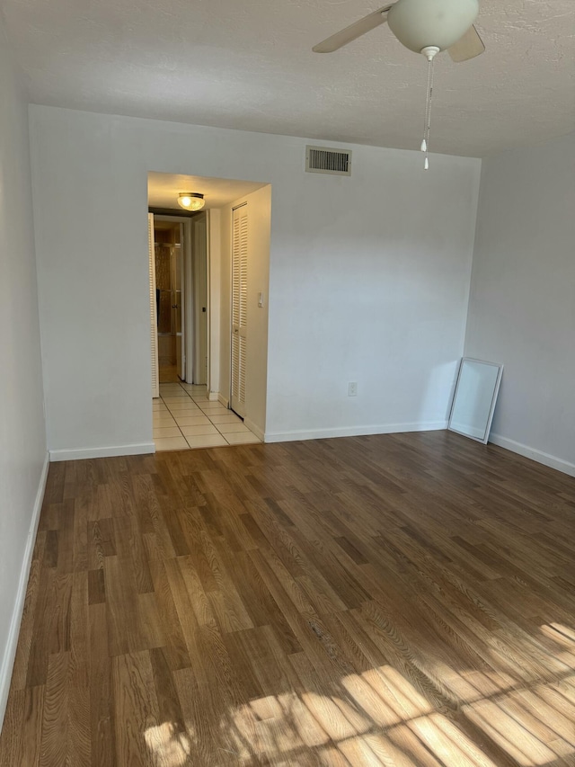 spare room with baseboards, wood finished floors, visible vents, and ceiling fan
