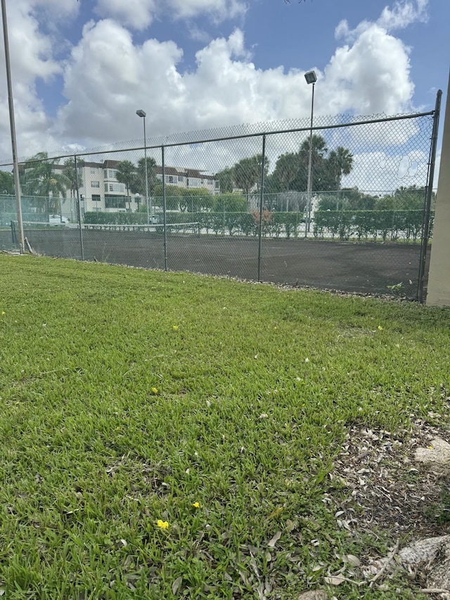 view of sport court featuring fence and a yard
