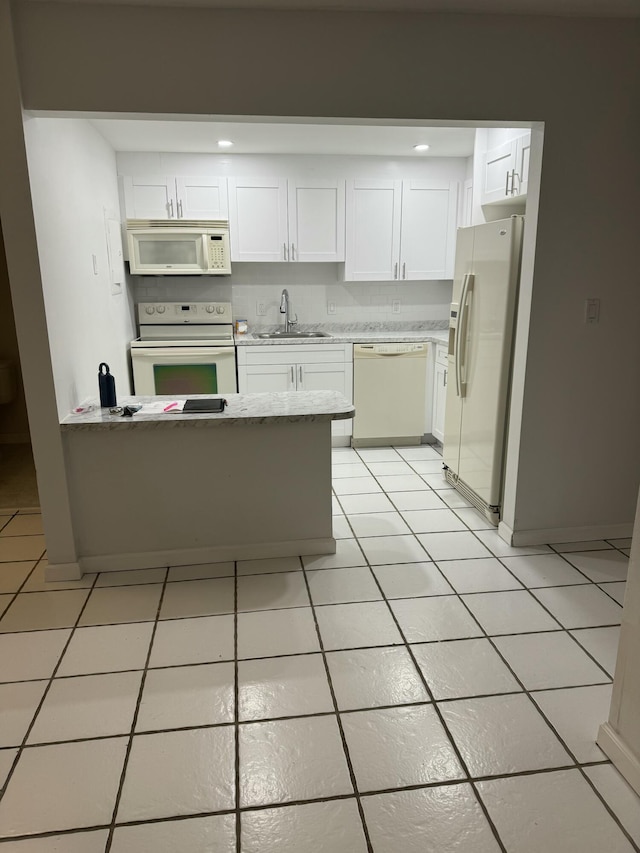 kitchen with white cabinets, light tile patterned floors, a sink, white appliances, and a peninsula