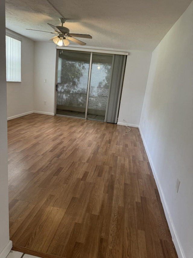 unfurnished room featuring ceiling fan, baseboards, wood finished floors, and a textured ceiling