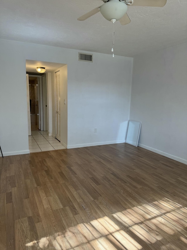 spare room with light wood-style flooring, visible vents, baseboards, and ceiling fan