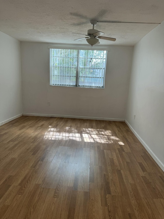 unfurnished room with wood finished floors, a textured ceiling, baseboards, and ceiling fan