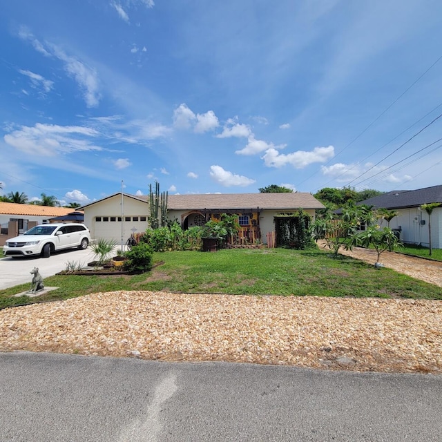 2379 Carambola Rd, West Palm Beach, FL 33406 - ranch-style house with driveway, a front yard, an attached garage, and stucco siding