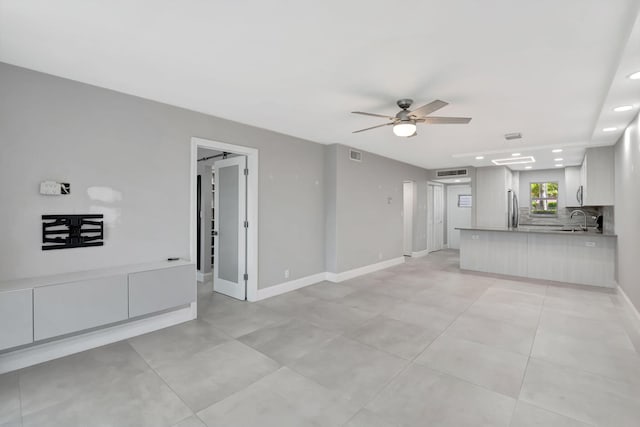 unfurnished living room featuring recessed lighting, baseboards, a sink, visible vents, and a ceiling fan