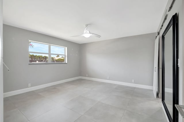 unfurnished bedroom featuring baseboards, a barn door, and ceiling fan