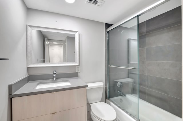 full bathroom with visible vents, toilet, vanity, and shower / bath combination with glass door