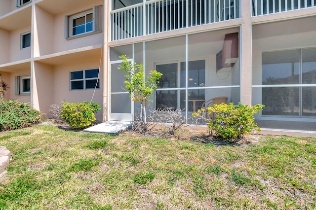 entrance to property with stucco siding and a yard