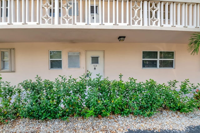 view of exterior entry with a balcony and stucco siding
