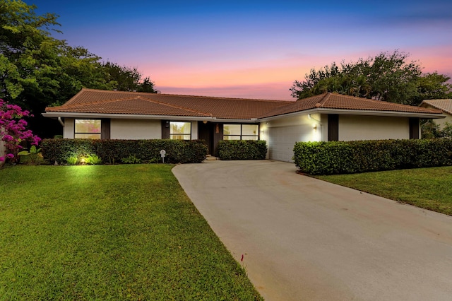 view of front of house featuring a tile roof, a garage, concrete driveway, a front yard, and stucco siding