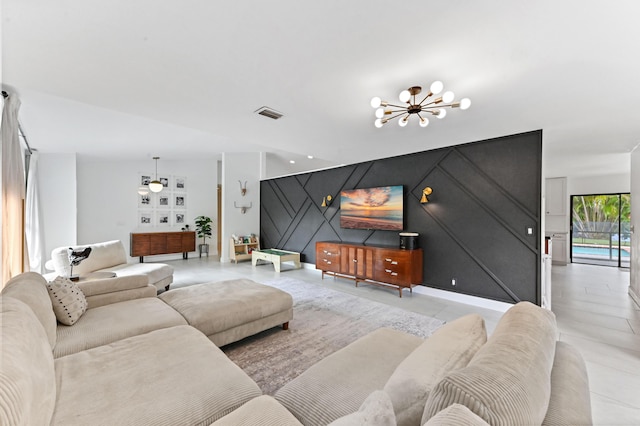 living room with tile patterned flooring, visible vents, an accent wall, and a notable chandelier