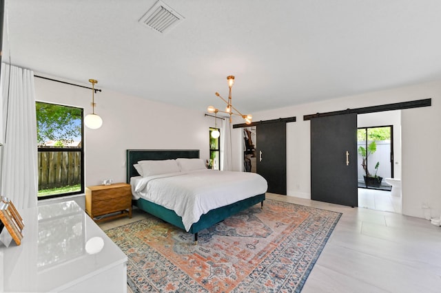 bedroom featuring a barn door, visible vents, and multiple windows