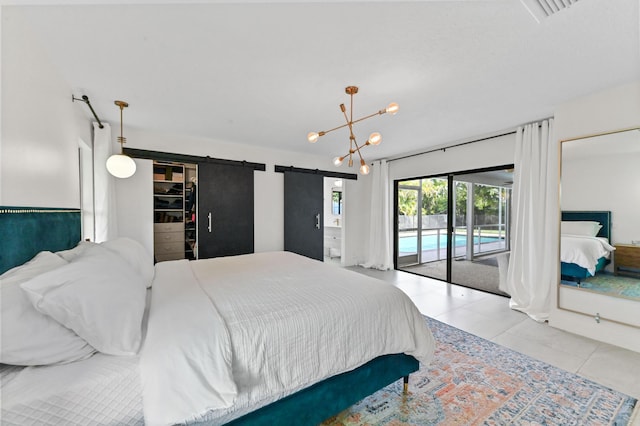 bedroom with a barn door, access to exterior, an inviting chandelier, tile patterned flooring, and a walk in closet