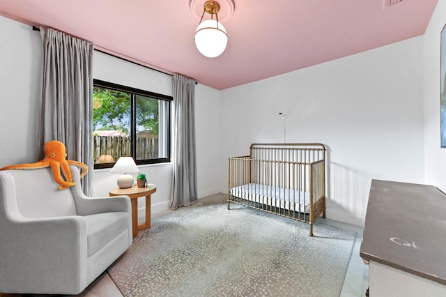bedroom featuring a nursery area and baseboards