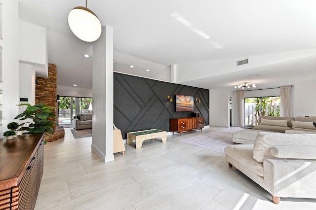living area featuring recessed lighting, an accent wall, plenty of natural light, and visible vents