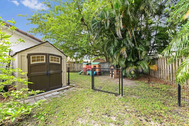 view of yard with a fenced backyard, an outdoor structure, a shed, and a playground
