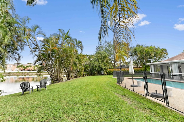 view of yard featuring a water view, a fenced in pool, a patio, and fence
