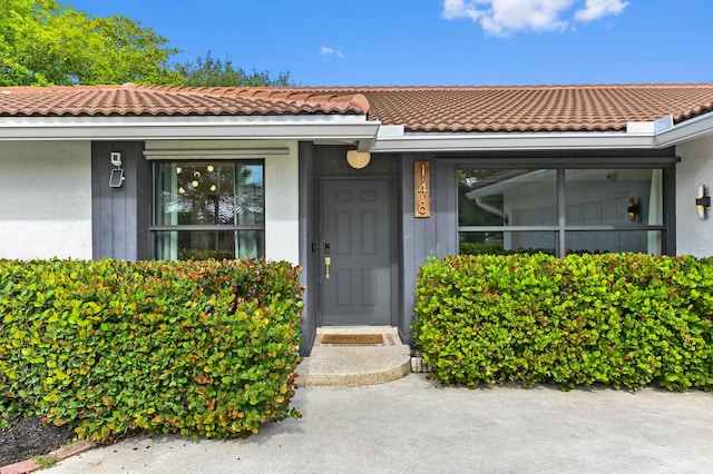 doorway to property featuring a tile roof and stucco siding