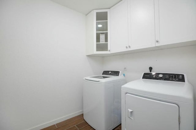 washroom featuring baseboards, independent washer and dryer, dark wood finished floors, and cabinet space
