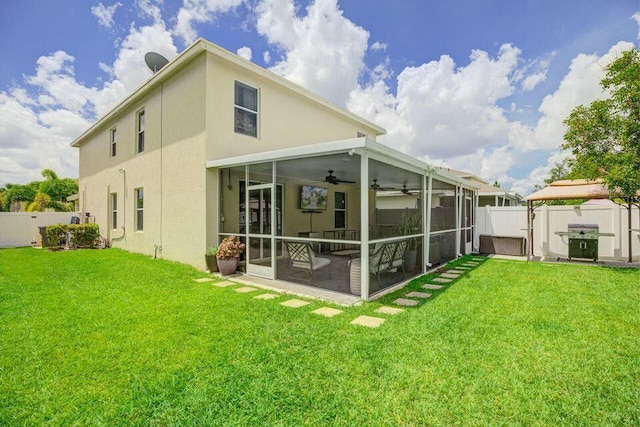rear view of house featuring a fenced backyard, a sunroom, a ceiling fan, and a yard