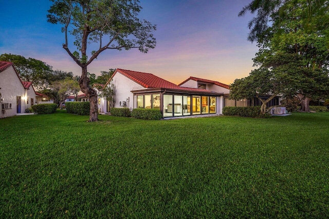 21481 Cypress Hammock Dr Unit 31B, Boca Raton, FL 33428 - back of house at dusk with a yard, a tile roof, a sunroom, and stucco siding