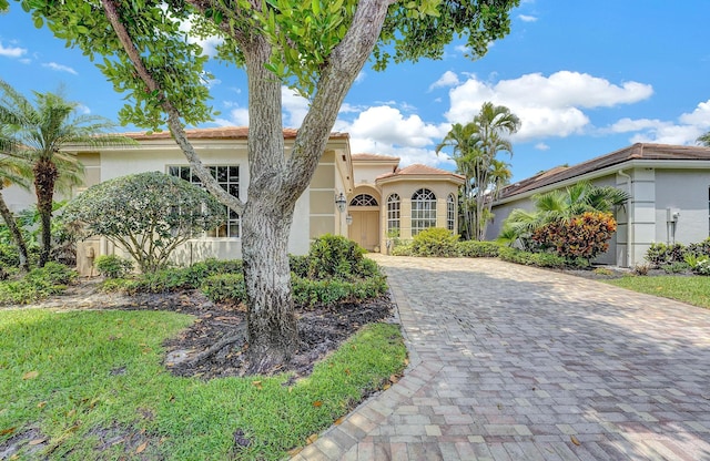 mediterranean / spanish-style home featuring stucco siding, decorative driveway, and a tile roof