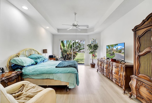 bedroom with a raised ceiling, access to exterior, recessed lighting, ceiling fan, and light wood finished floors