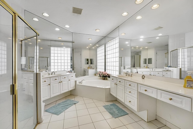 bathroom with a shower stall, a garden tub, recessed lighting, two vanities, and tile patterned floors
