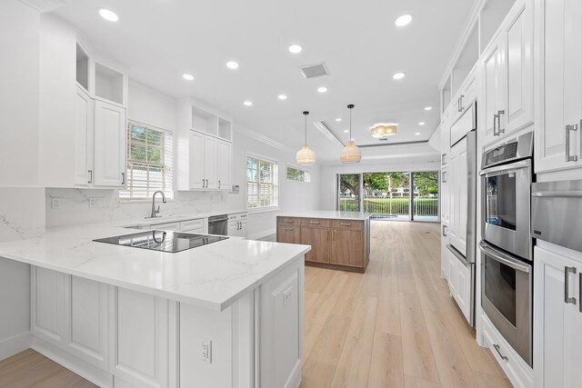 17065 Bay St, Jupiter, FL 33477 - kitchen with visible vents, white cabinets, appliances with stainless steel finishes, crown molding, and backsplash