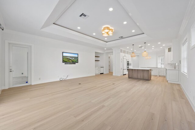 17065 Bay St, Jupiter, FL 33477 - unfurnished living room featuring crown molding, visible vents, a raised ceiling, and light wood-style floors