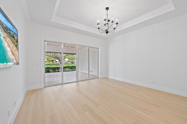 17065 Bay St, Jupiter, FL 33477 - empty room featuring baseboards, a raised ceiling, a notable chandelier, crown molding, and light wood finished floors