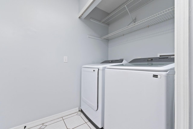 laundry area featuring independent washer and dryer, laundry area, light tile patterned floors, and baseboards