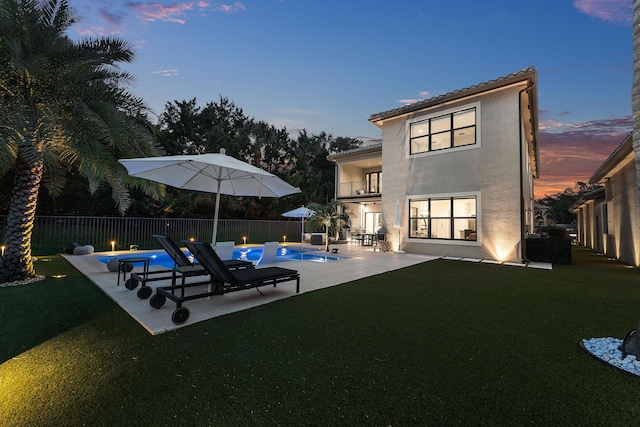 16491 Gateway Bridge Dr, Delray Beach, FL 33446 - back of property at dusk with a balcony, stucco siding, a patio, and a tiled roof