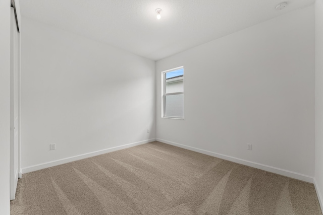 spare room featuring baseboards and light colored carpet