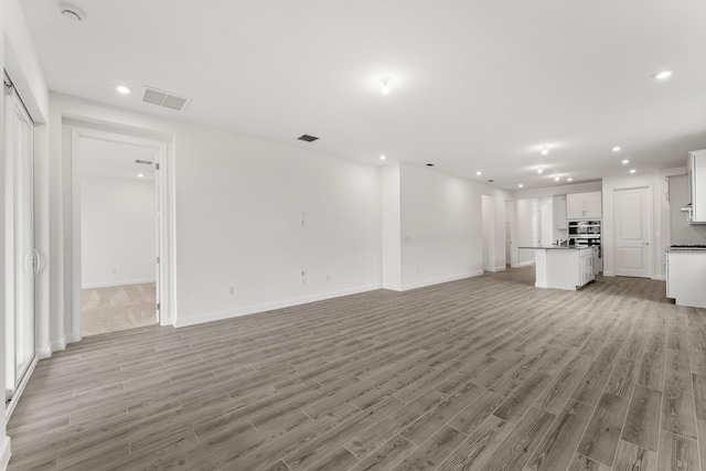 unfurnished living room with visible vents, baseboards, light wood finished floors, and recessed lighting