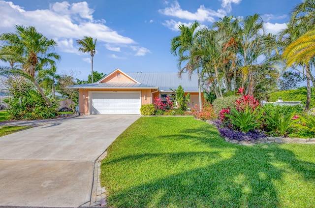 9208 SE Gettysburg Ct, Hobe Sound, FL 33455 - view of front of home with a front lawn, concrete driveway, a garage, and metal roof
