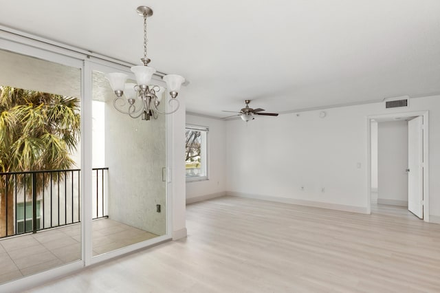 empty room featuring ceiling fan with notable chandelier, visible vents, wood finished floors, and baseboards