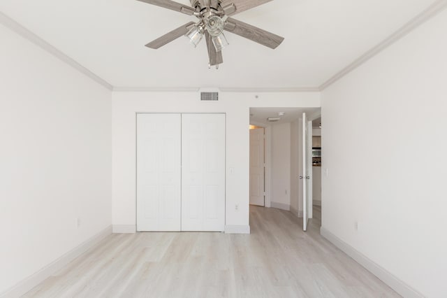 unfurnished bedroom with ornamental molding, baseboards, visible vents, light wood-style flooring, and a closet