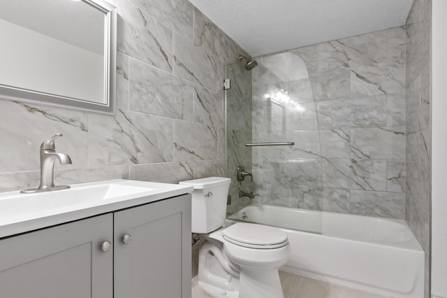full bathroom with toilet, vanity, a textured ceiling, tub / shower combination, and tile walls