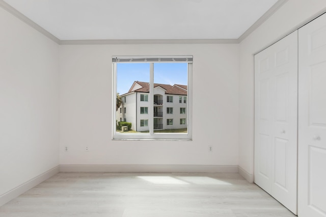 unfurnished bedroom with a closet, baseboards, ornamental molding, and wood finished floors
