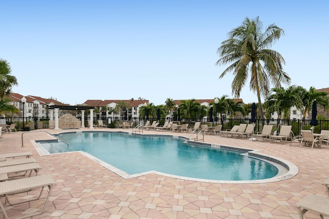 community pool with fence and a patio area