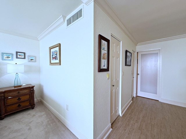 hall with baseboards, visible vents, ornamental molding, and wood finished floors