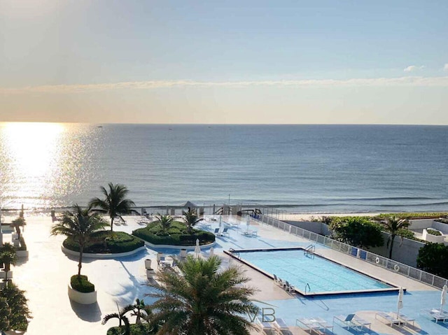 community pool with fence, a water view, and a patio area