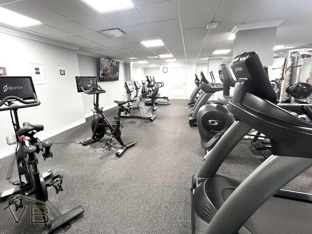 workout area with a drop ceiling, crown molding, and baseboards