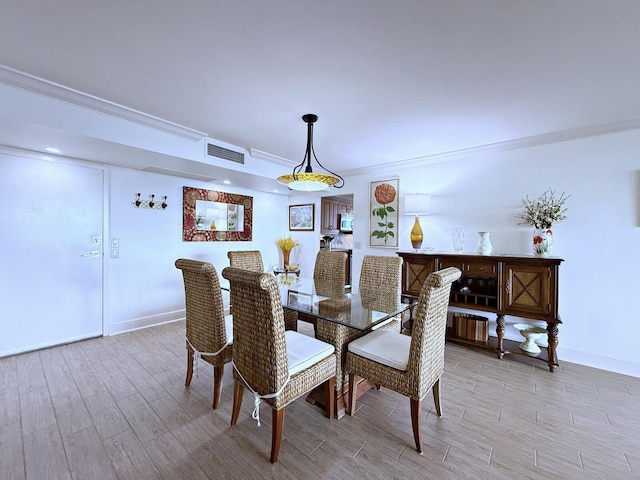 dining room featuring ornamental molding, visible vents, light wood-style flooring, and baseboards