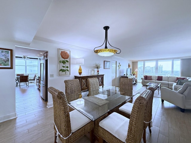 dining area with crown molding, light wood-style flooring, and baseboards
