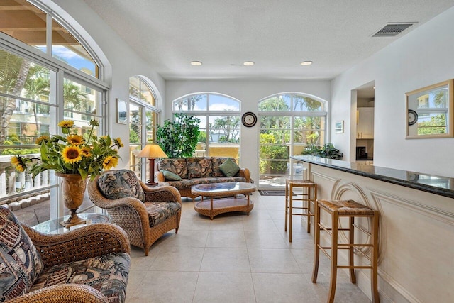 living area featuring visible vents, recessed lighting, light tile patterned floors, and a textured ceiling