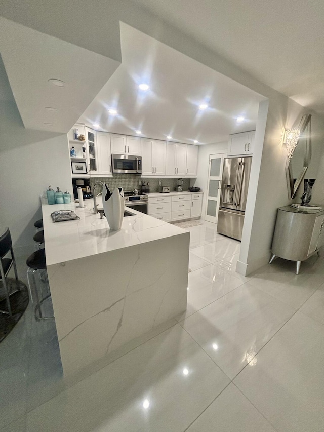 3400 S Ocean Blvd Unit 3H, Highland Beach, FL 33487 - kitchen featuring stainless steel appliances, a peninsula, light stone counters, and white cabinets