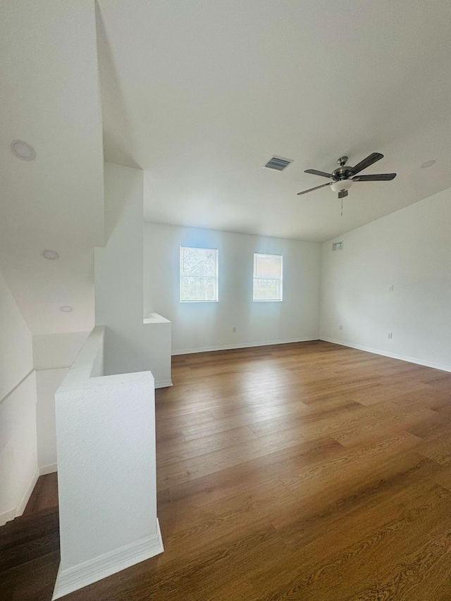 unfurnished room featuring a ceiling fan, baseboards, visible vents, and wood finished floors